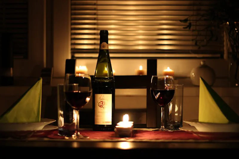 Candlelit table set for two at home with wine glasses and candles — a romantic date night idea