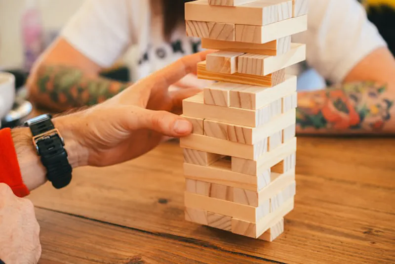 Two people playing Jenga together on a wooden table — a fun games night date idea at home